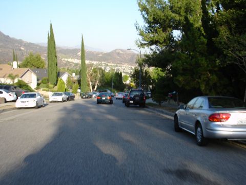 1993 Ford Taurus - A silver sedan is parked on the right side of a residential street lined with trees and houses.
