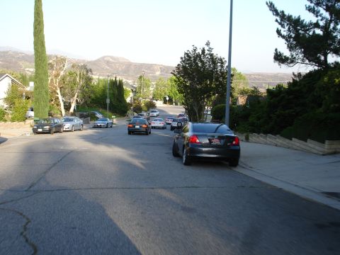1993 Ford Taurus - Several cars are parked along a street in a residential neighborhood with hills in the background.