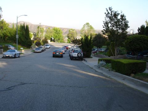 1993 Ford Taurus - A residential street scene shows multiple vehicles parked and in motion under a clear sky.