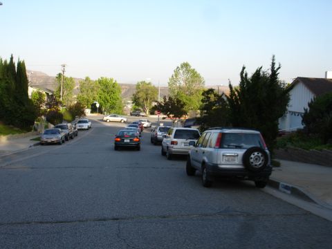 1993 Ford Taurus - Multiple vehicles are parked along a suburban street under a clear sky.