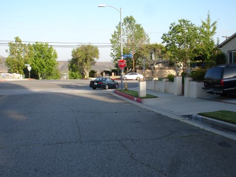1993 Ford Taurus - A dark sedan makes a left turn at an intersection with a stop sign, while a white sedan and a black SUV are also visible.