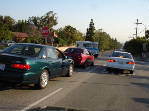 1993 Ford Taurus - A green 1993 Ford Taurus coupe is seen from the rear quarter angle, stopped in traffic behind other vehicles.