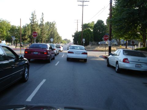 1993 Ford Taurus - Several cars are lined up on a road, waiting at a stop sign.