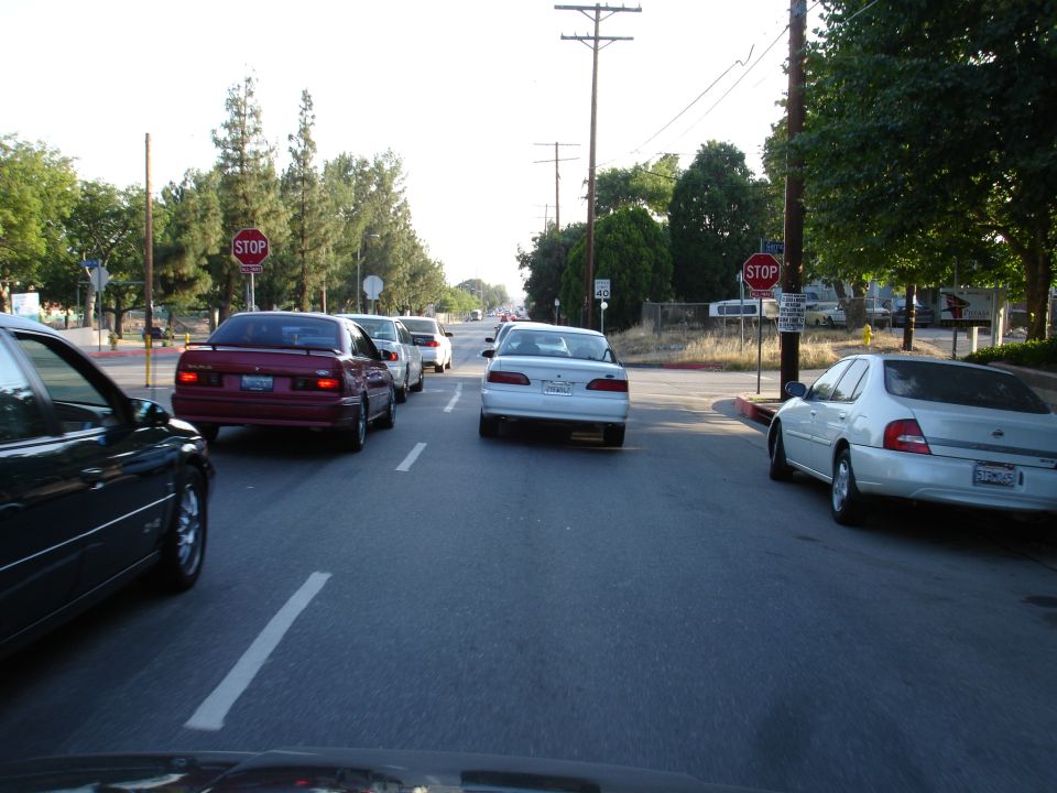 Cars stopped at a stop sign on a sunny day