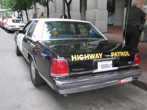 1991 Ford LTD Crown Victoria - Rear three-quarter of a black Ford Crown Victoria Highway Patrol sedan with California plate 888849 and yellow HIGHWAY PATROL lettering.