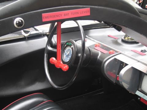 1991 Ford LTD Crown Victoria - Batmobile replica steering wheel fitted with a red 'EMERGENCY BAT TURN LEVER' and a round gauge above a silver finned console.