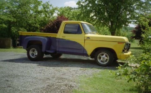 1981 Ford Bronco - This two-tone Ford F-Series pickup truck is parked on a gravel driveway with trees in the background.