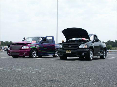 2001 Mercury Grand Marquis - Two Ford F-150 Lightning trucks are displayed at an outdoor car show.