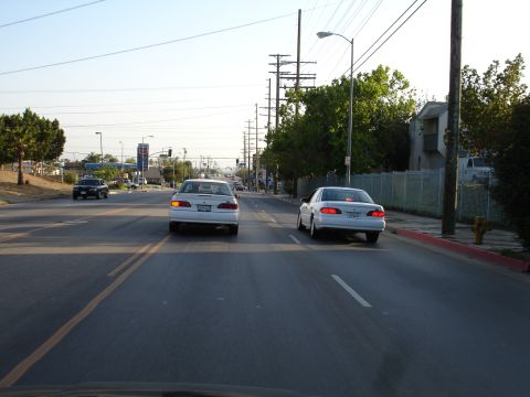1993 Ford Taurus - Two white sedans, one identified as a 1993 Ford Taurus, travel down a suburban street.