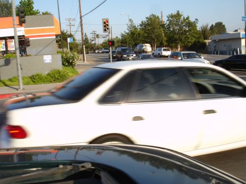 1993 Ford Taurus - A white sedan drives past a traffic light at an intersection with other vehicles visible.