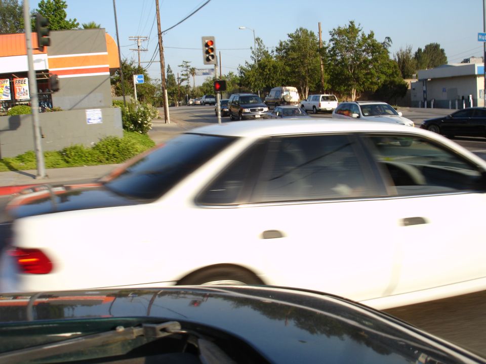 White sedan in motion, side view, showing a distinctive rear window and C-pillar shape