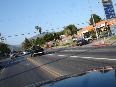 1993 Ford Taurus - A black pickup truck is seen driving on a road with a gas station in the background displaying prices.