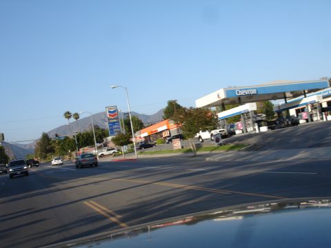 1993 Ford Taurus - A street scene captures a Chevron gas station under a clear blue sky, with mountains visible in the distance.