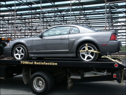 2001 Mercury Grand Marquis - Gray 2001 Ford Mustang GT being towed on a flatbed truck, with bleachers visible in the background.