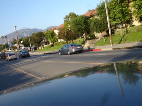 1993 Ford Taurus - A silver sedan is seen from behind driving down a street with other cars present.