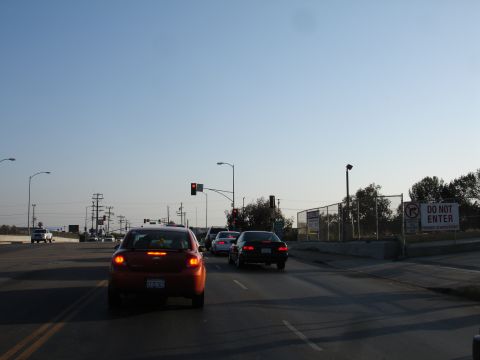 1993 Ford Taurus - A red car is stopped at a traffic light in a busy intersection with multiple vehicles.