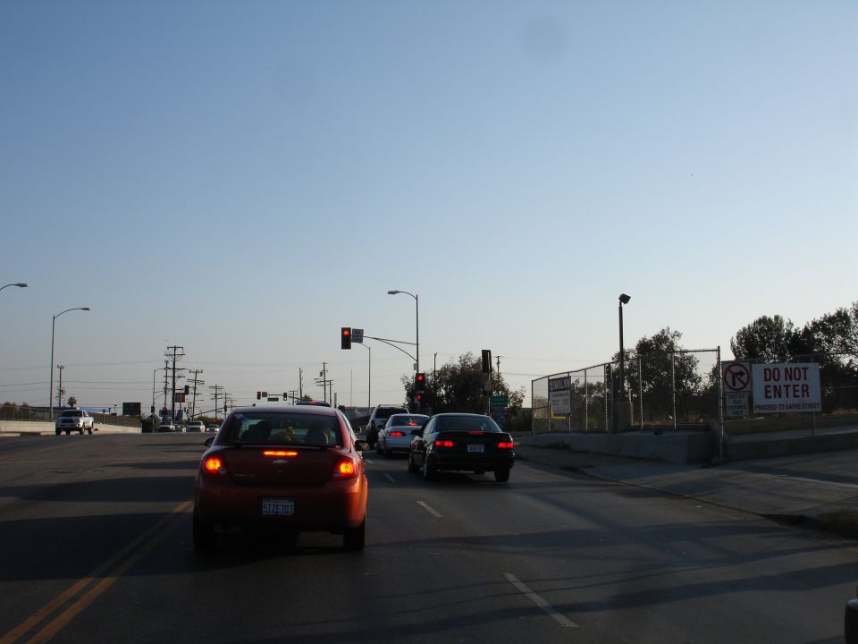 Red car's rear end, traffic light, and a 'Do Not Enter' sign