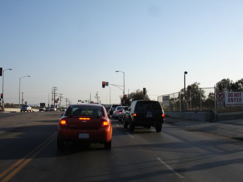 1993 Ford Taurus - Traffic moves slowly under a clear sky, with a red sedan and a black SUV visible in the foreground.