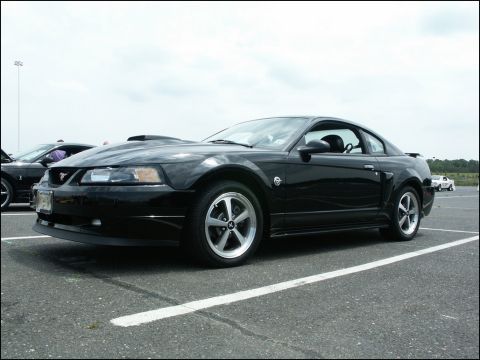 2001 Mercury Grand Marquis - A black Ford Mustang is parked at an outdoor event, with another car visible behind it.