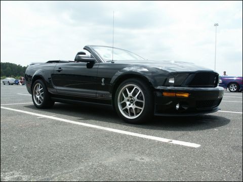 2001 Mercury Grand Marquis - A black convertible Mustang GT 500 is parked in a lot with other vehicles visible in the background.