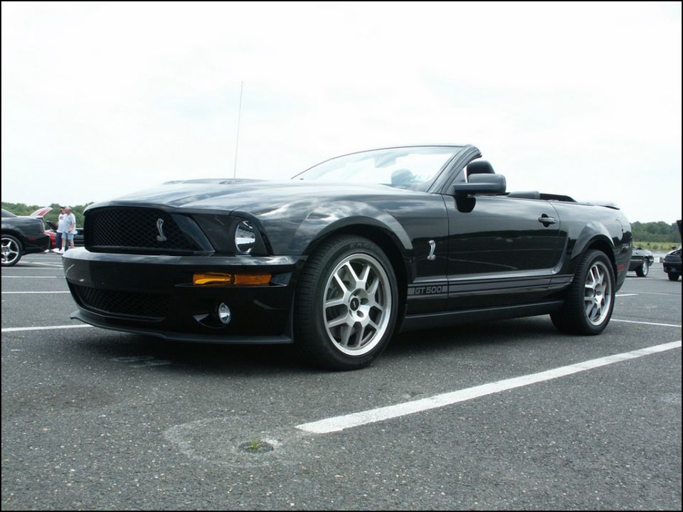 Black convertible Ford Mustang GT500 parked in a lot, side view showing GT500 stripe