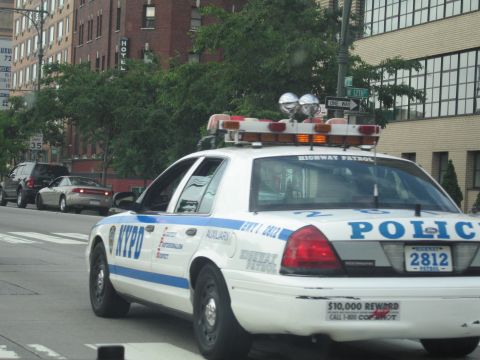 1991 Ford LTD Crown Victoria - white and blue NYPD Highway Patrol Ford Crown Victoria, unit 2812, drives along an urban street past brick buildings.