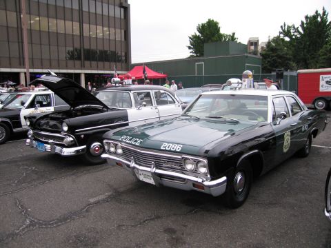 1991 Ford LTD Crown Victoria - green-and-white vintage police sedan marked POLICE 2086 parked beside other classic police cars at an outdoor show.