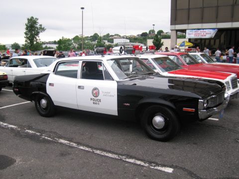1991 Ford LTD Crown Victoria - black-and-white police sedan marked POLICE with an LAPD-style door shield parked among classic cars at an outdoor show.