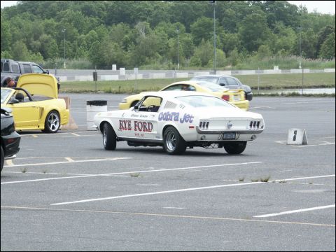 2001 Mercury Grand Marquis - White 1968 Mustang Cobra Jet race car with 'Rye Ford' graphics is parked at an event, with other vehicles nearby.