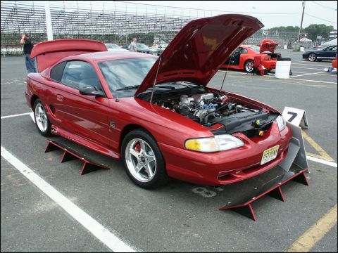 2001 Mercury Grand Marquis - A red 1994 Ford Mustang coupe is displayed with its hood open, revealing the engine, at a car show.