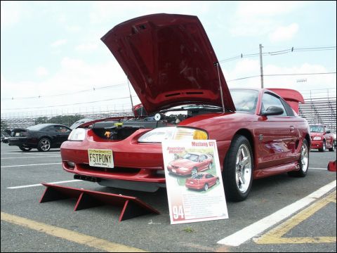 2001 Mercury Grand Marquis - Red 1994 Ford Mustang GT displayed at a car show with its hood open and a descriptive sign.