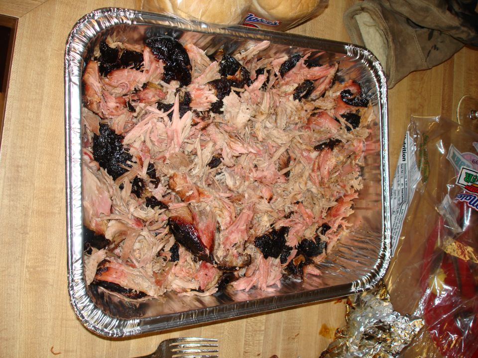 Aluminum pan of smoked pulled pork on a wooden table
