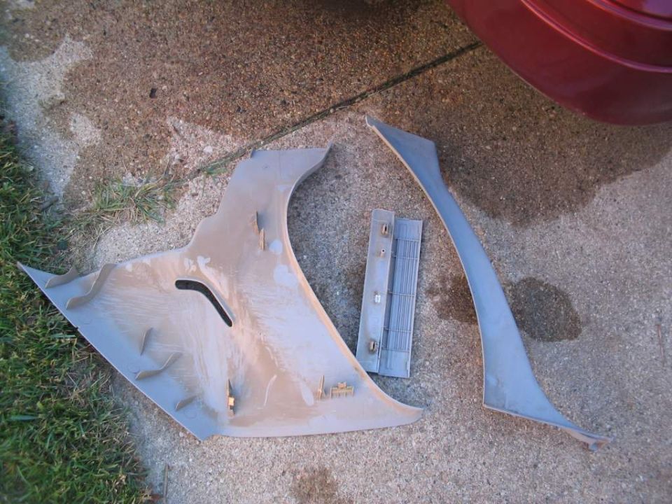Gray plastic vehicle trim pieces laid on a driveway