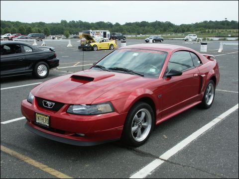 2001 Mercury Grand Marquis - A red Ford Mustang GT is parked in a lot, with other vehicles visible in the background.