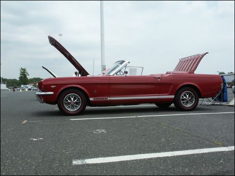 2001 Mercury Grand Marquis - Side view of a red 1965 Ford Mustang convertible at a car show.