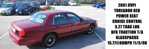 2001 Ford Crown Victoria - A red 2001 Ford Crown Victoria is parked in a lot with other vehicles visible in the background.