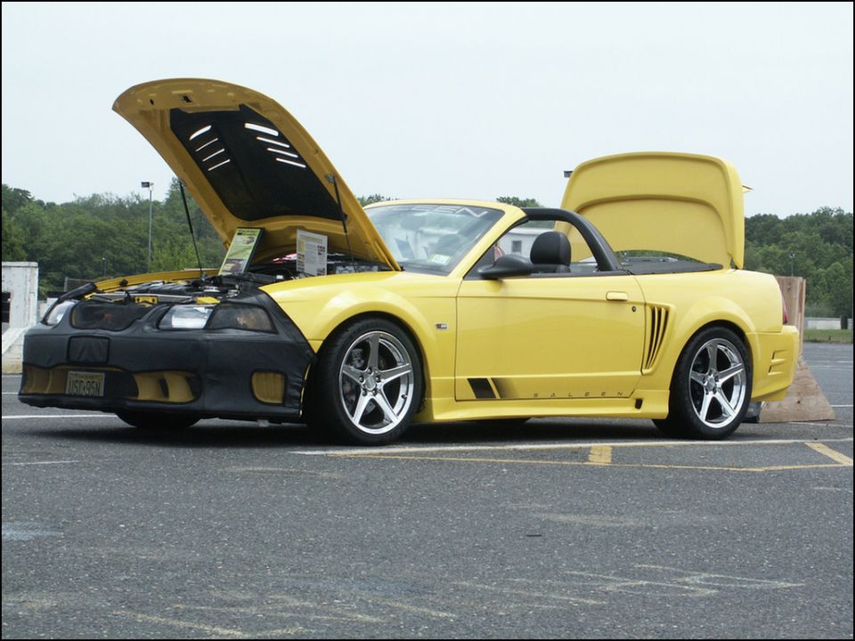 Yellow convertible with hood and trunk open, showing engine and interior