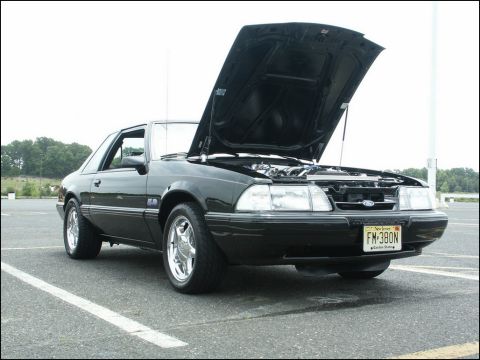 2001 Mercury Grand Marquis - A black Ford Mustang is parked with its hood open, revealing the engine compartment.