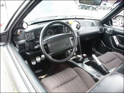 2001 Mercury Grand Marquis - The interior of a car is shown, aftermarket gauges and a Ford logo on the floor mat. Other vehicles are visible through the windows.