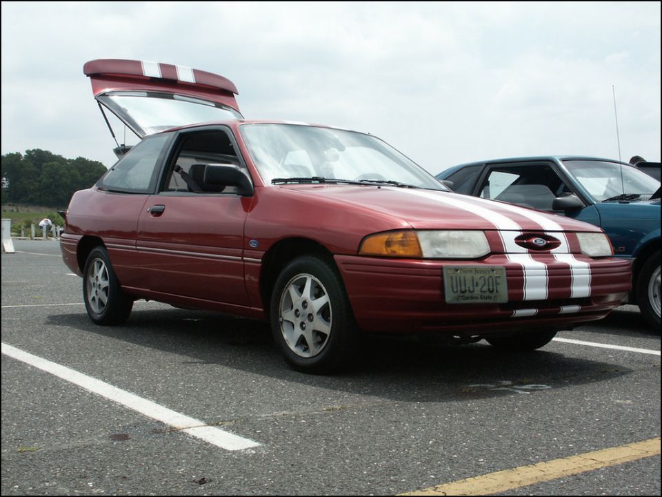 Red hatchback with white racing stripes on hood and trunk, parked next to another car