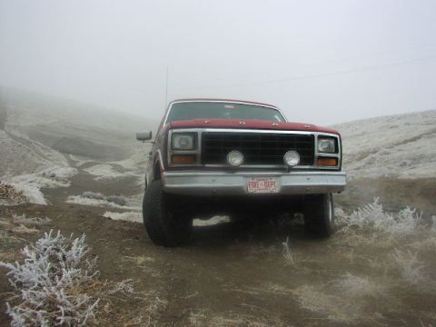 1981 Ford Bronco - A red pickup truck sits on a dirt road, partially obscured by fog, with a license plate indicating "FIRE DEPT".