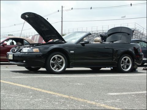 2001 Mercury Grand Marquis - Black convertible Mustang with hood and trunk open at a car show.