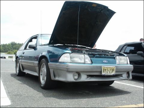 2001 Mercury Grand Marquis - A teal Ford Mustang is parked with its hood up, revealing the engine bay.