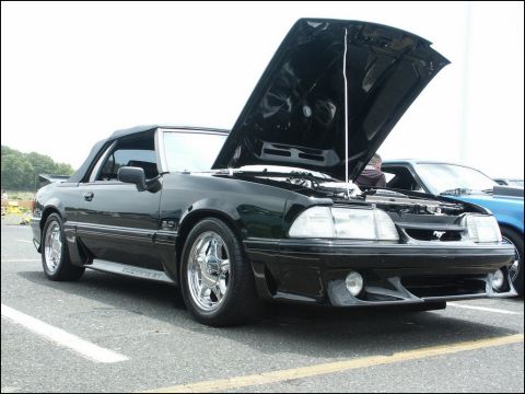 2001 Mercury Grand Marquis - A black 1987 Ford Mustang GT convertible is parked with its hood open, revealing the engine bay.