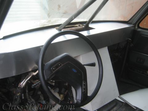 1990 Ford Bronco - interior of a vehicle under restoration shows a steering wheel with a Ford emblem and a stripped, primered dashboard.