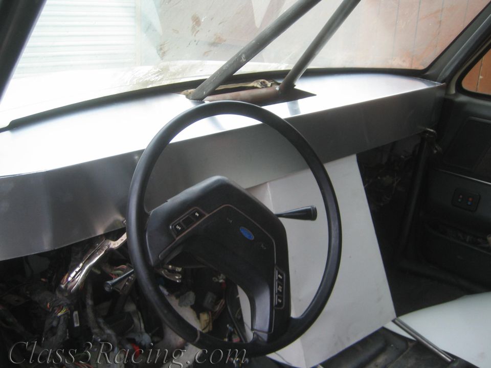 Interior of a vehicle showing steering wheel with Ford emblem and bare dash