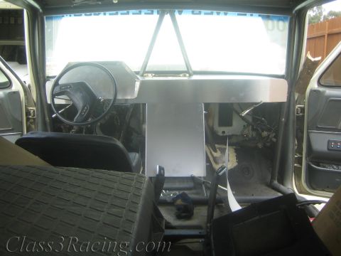 1990 Ford Bronco - Stripped vehicle interior viewed toward the dash, with a fabricated aluminum center console and exposed floor.