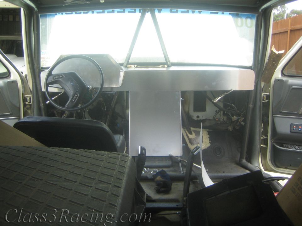 Bare cabin interior with center aluminum console and steering wheel under windshield
