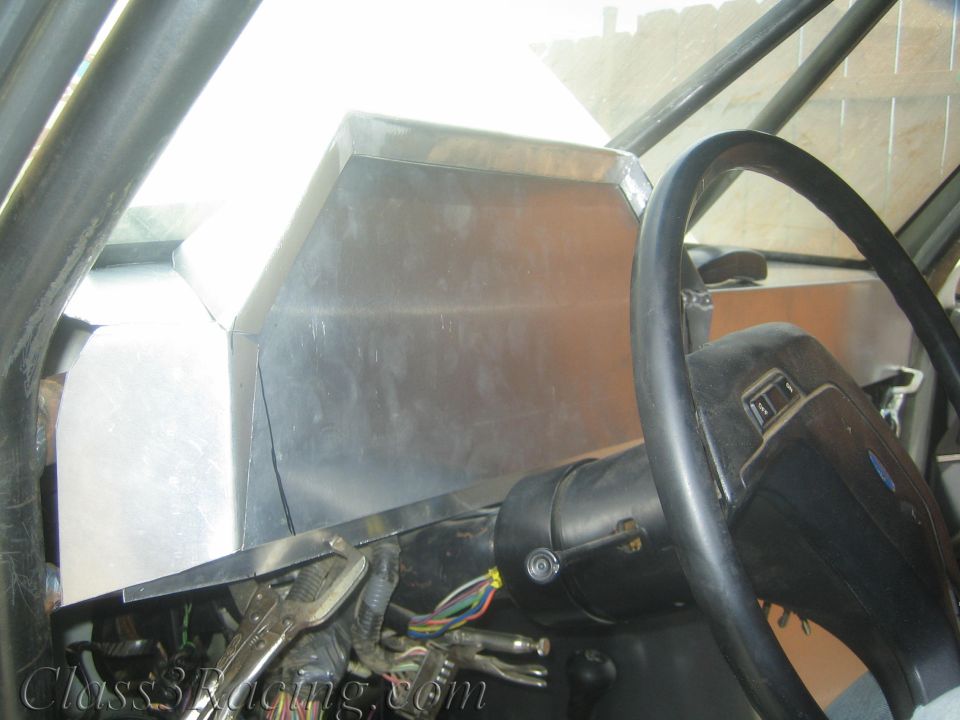 Aluminum dash panel and Ford steering wheel inside a stripped vehicle cabin