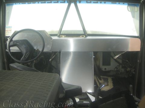 1990 Ford Bronco - Bare vehicle interior with a fabricated aluminum dashboard, steering wheel and front bench seat lit by daylight.